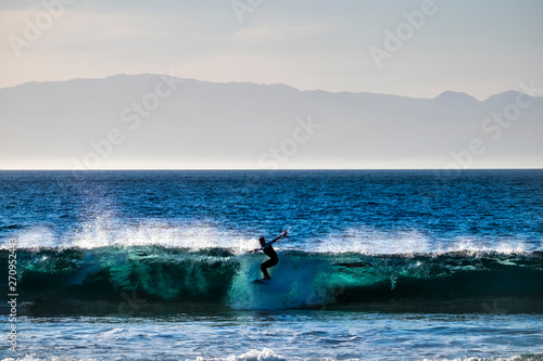 teenager surfing at the wave in tenerife playa de las americas - white wetsuits and beautiful and perfect wave