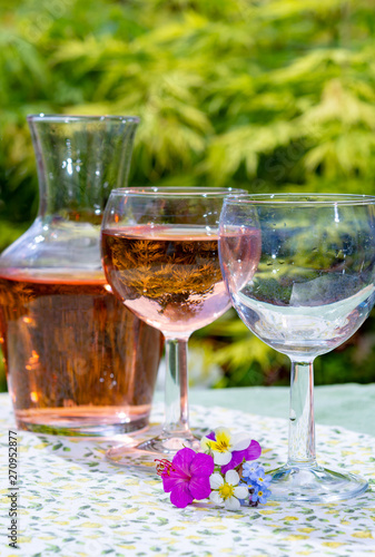 Wine carafe and glasses with cold rose wine and wild flowers in summer sunny day