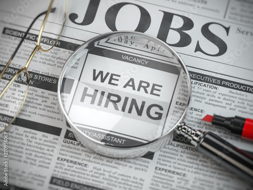 We are hiring. Job search and employment concept. Magnified glass with jobs classified ads in newspaper,