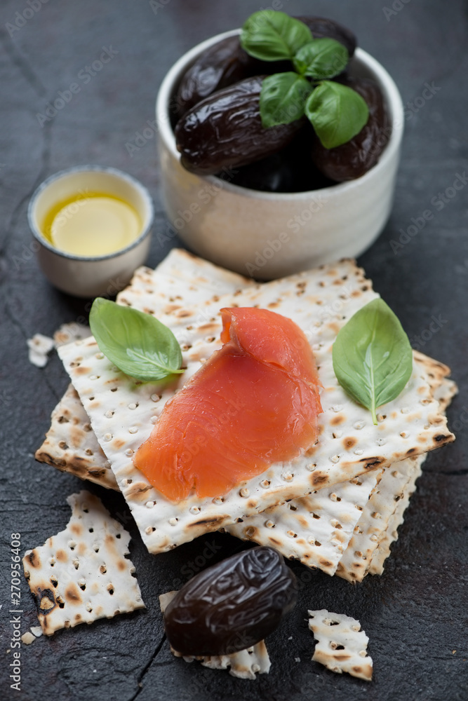 Close-up of matzoh bread with salmon fillet and dates, vertical shot, selective focus Close-up of matzoh bread with salmon fillet and dates, vertical shot, selective focus