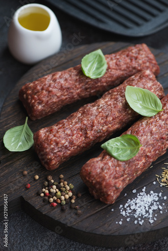 Raw marbled beef kabobs with seasonings on a wooden cutting board, close-up, vertical shot