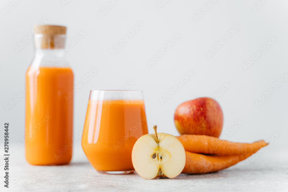 Horizontal shot of detox carrot juice in bottle and glass, slice of apple, carrot, isolated over white background. Healthy natural drink. Selective focus Horizontal shot of detox carrot juice in bottle and glass, slice of apple, carrot, isolated over white background. Healthy natural drink. Selective focus