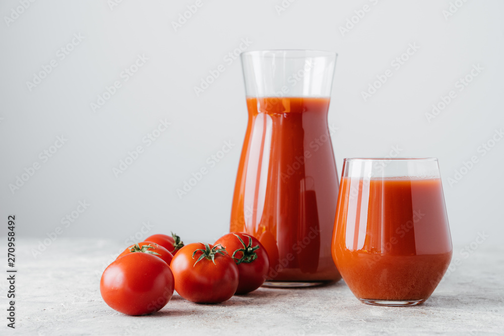 Raw tomatoes and glass of freshly drink, isolated over white background. Tomato juice made of vegetables in transparent glasses. Healthy drink Raw tomatoes and glass of freshly drink, isolated over white background. Tomato juice made of vegetables in transparent glasses. Healthy drink