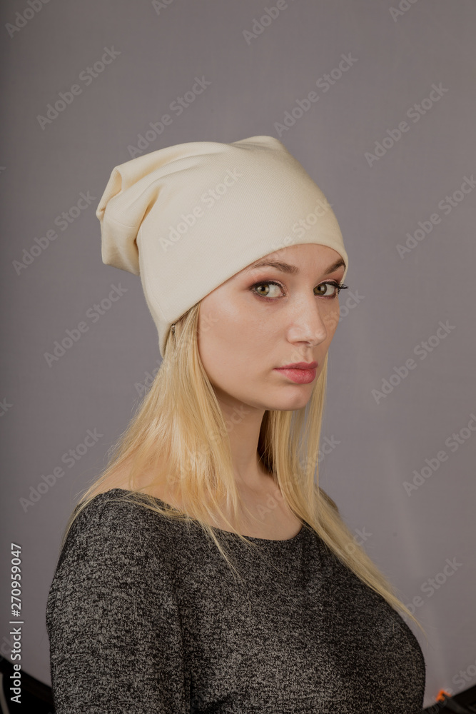 Portrait of a beautiful young girl in a stylish headdress with natural makeup on a gray background. Portrait of a beautiful young girl in a stylish headdress with natural makeup on a gray background.
