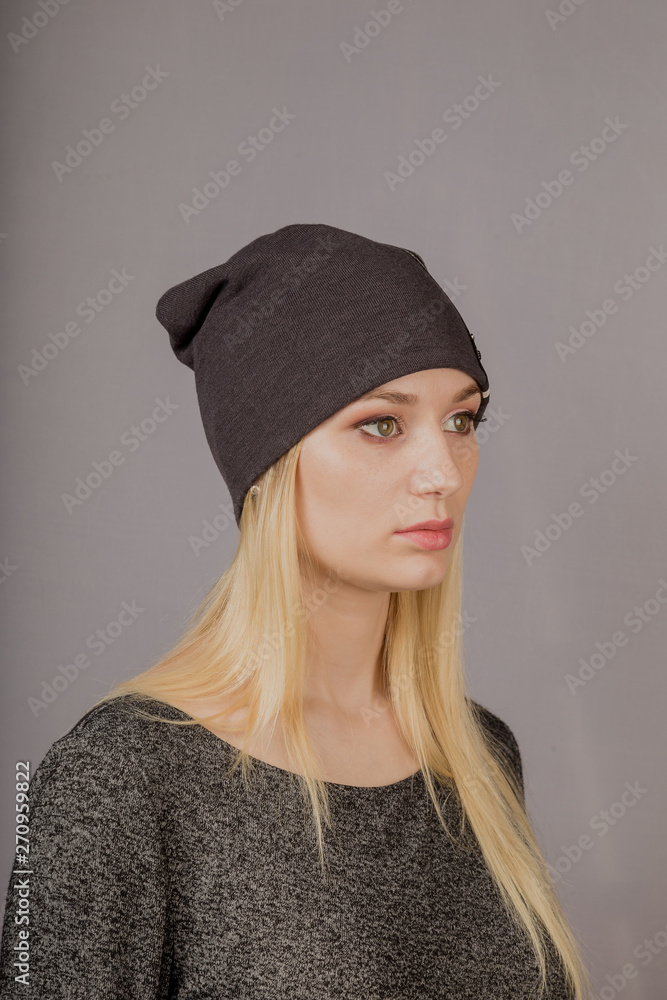 Portrait of a beautiful young girl in a stylish headdress with natural makeup on a gray background. Portrait of a beautiful young girl in a stylish headdress with natural makeup on a gray background.