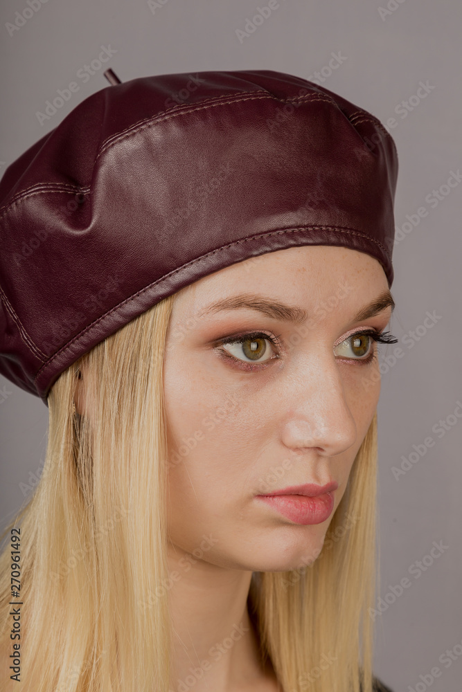 Portrait of a beautiful young girl in a stylish headdress with natural makeup on a gray background. Portrait of a beautiful young girl in a stylish headdress with natural makeup on a gray background.