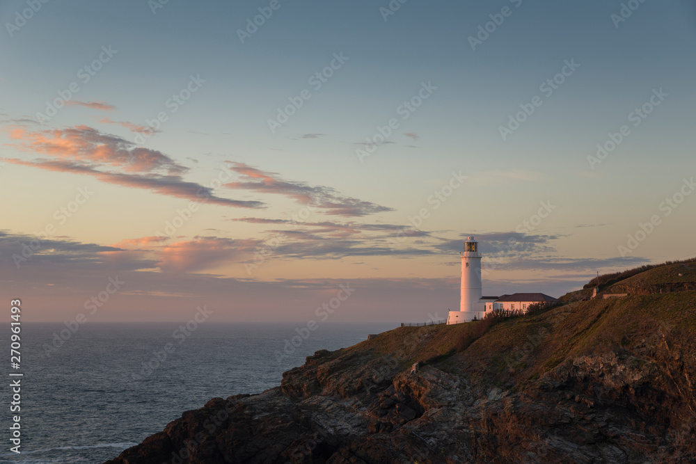 Lighthouse at sunset by the ocean on Cornwalls North coast, uk