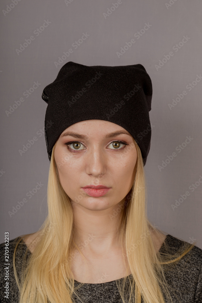 Portrait of a beautiful young girl in a stylish headdress with natural makeup on a gray background. Portrait of a beautiful young girl in a stylish headdress with natural makeup on a gray background.