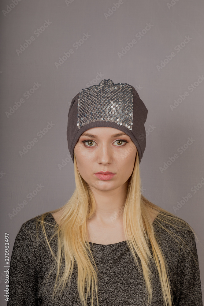 Portrait of a beautiful young girl in a stylish headdress with natural makeup on a gray background. Portrait of a beautiful young girl in a stylish headdress with natural makeup on a gray background.