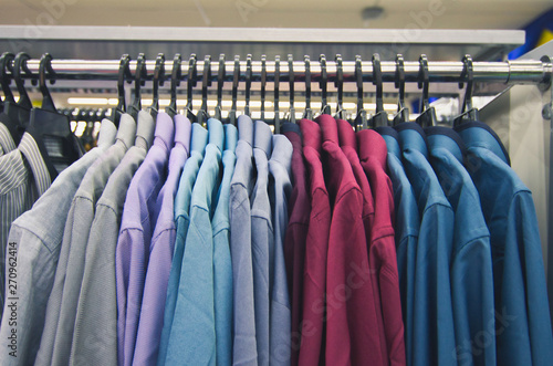 Colorful selection of clothes for  men hanging on hangers in shopping mall for store sale concept © amirul syaidi