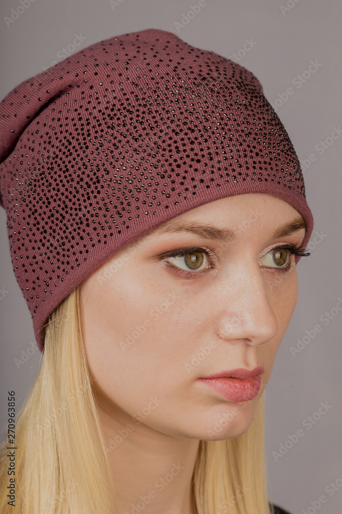 Portrait of a beautiful young girl in a stylish headdress with natural makeup on a gray background. Portrait of a beautiful young girl in a stylish headdress with natural makeup on a gray background.