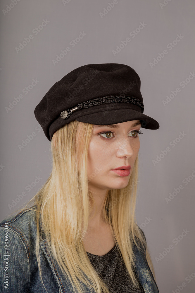 Portrait of a beautiful young girl in a stylish headdress with natural makeup on a gray background. Portrait of a beautiful young girl in a stylish headdress with natural makeup on a gray background.