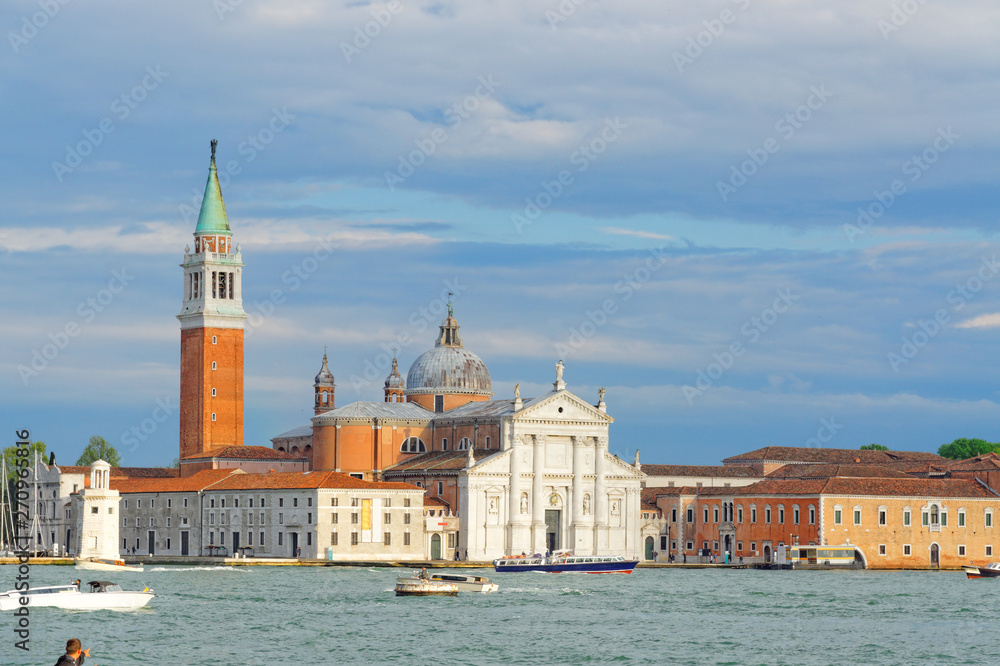 Boats flowing between the islands with a beautiful historic church in Venice, Italy.