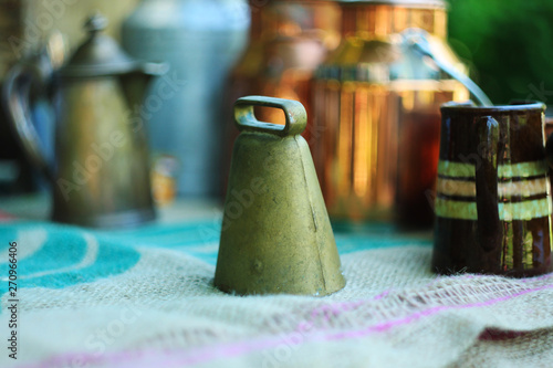 Antique caw bell, metal jugs and milk cans on linen tablecloth. photo