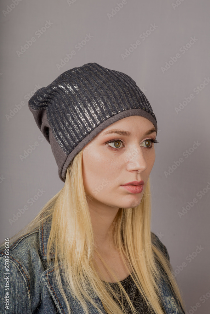 Portrait of a beautiful young girl in a stylish headdress with natural makeup on a gray background.