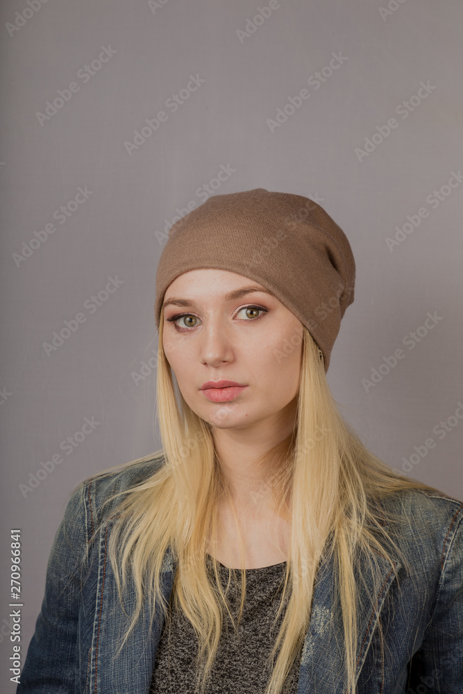 Portrait of a beautiful young girl in a stylish headdress with natural makeup on a gray background. Portrait of a beautiful young girl in a stylish headdress with natural makeup on a gray background.