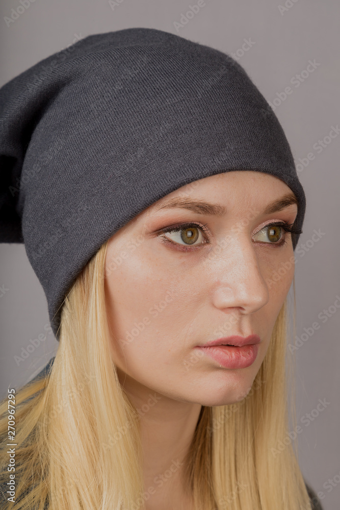 Portrait of a beautiful young girl in a stylish headdress with natural makeup on a gray background. Portrait of a beautiful young girl in a stylish headdress with natural makeup on a gray background.