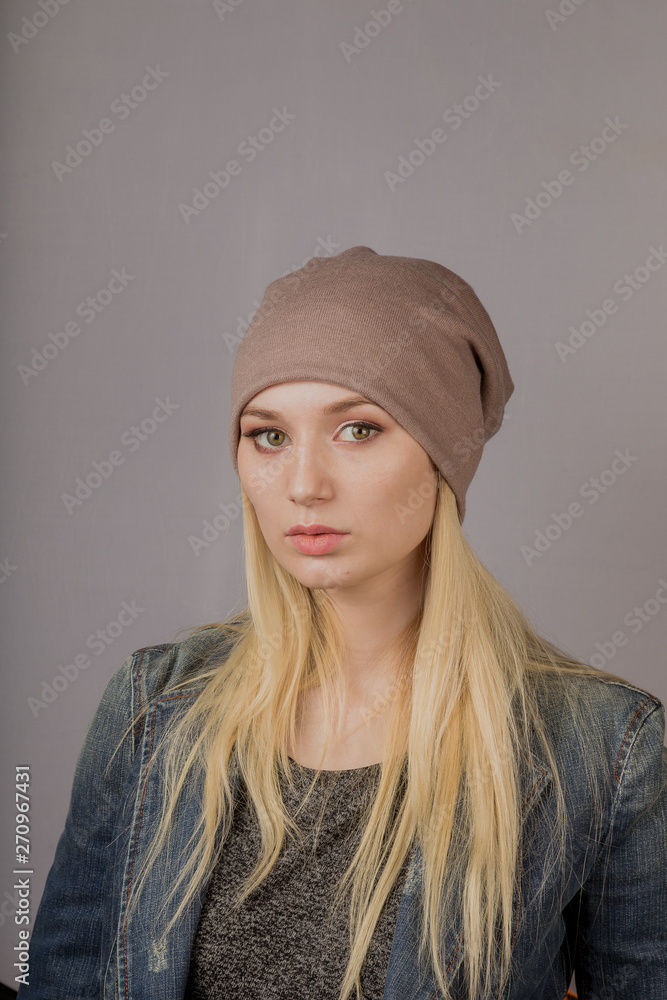 Portrait of a beautiful young girl in a stylish headdress with natural makeup on a gray background. Portrait of a beautiful young girl in a stylish headdress with natural makeup on a gray background.