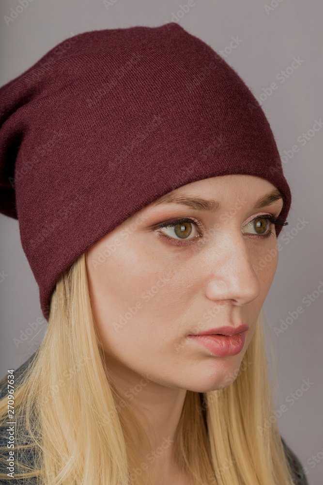 Portrait of a beautiful young girl in a stylish headdress with natural makeup on a gray background. Portrait of a beautiful young girl in a stylish headdress with natural makeup on a gray background.
