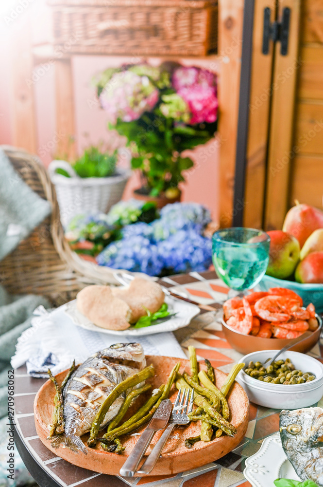 Dining table with different foods, snacks and flowers. Summer lunch in the open air. Seafood and vegetables.