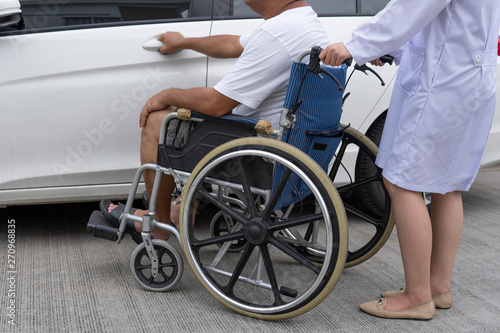 Helpful Female nurse with old man on wheelchair helping he get in to the car