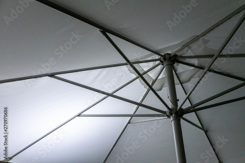 Metal Structure of an umbrella as abstract background. White umbrella with metal lines on a sunny day