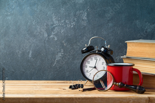 Back to school background with coffee cup, alarm clock and old books on wooden table