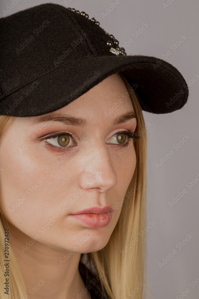 Portrait of a beautiful young girl in a stylish headdress with natural makeup on a gray background. Portrait of a beautiful young girl in a stylish headdress with natural makeup on a gray background.