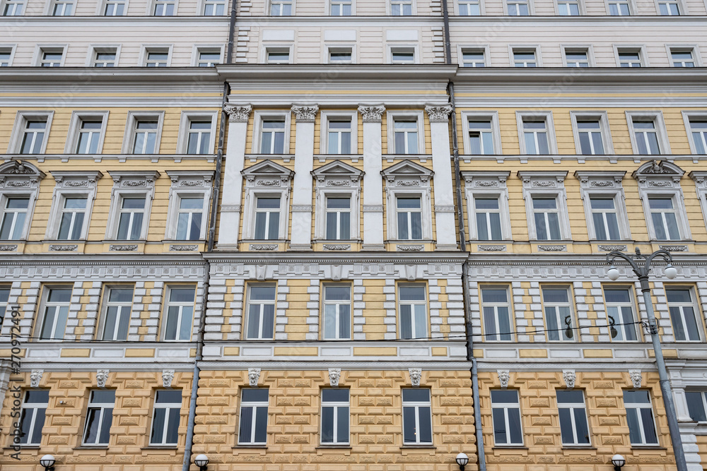 Obraz premium Several Windows in a row on the facade of the old building. Windows in a row on a marble wall. Rows of Windows on a tall building.