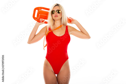 фотографія Pretty young blonde lifeguard in red sexy swimsuit with lifeguard rescue can floating buoy tube on the white background