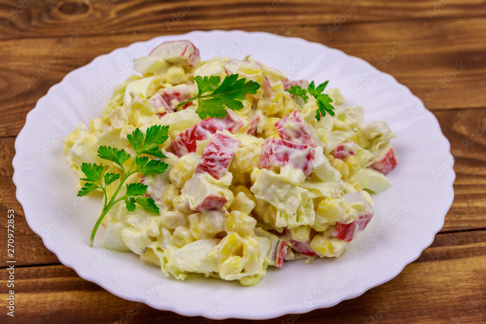 Salad with crab sticks, sweet corn, chinese cabbage, eggs and mayonnaise on wooden table Salad with crab sticks, sweet corn, chinese cabbage, eggs and mayonnaise on wooden table