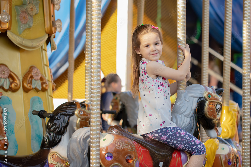 Girl riding on a merry go round. Little girl playing on carousel, summer fun, happy childhood and vacation concept Girl riding on a merry go round. Little girl playing on carousel, summer fun, happy childhood and vacation concept