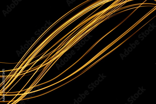 Long exposure, light painting photography. Vibrant streaks of metallic gold colour against a black background