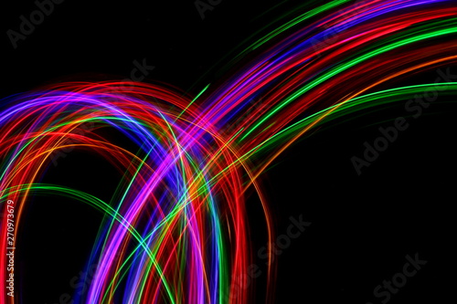 Long exposure, light painting photography. Multi color streaks and swirls of red, green and blue light against a black background.