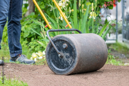 Mann walzt Boden mit Rasenwalze photo