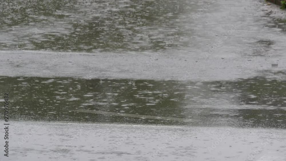 Rain falling down to wet asphalt road with passing cars and light reflection Rain falling down to wet asphalt road with passing cars and light reflection