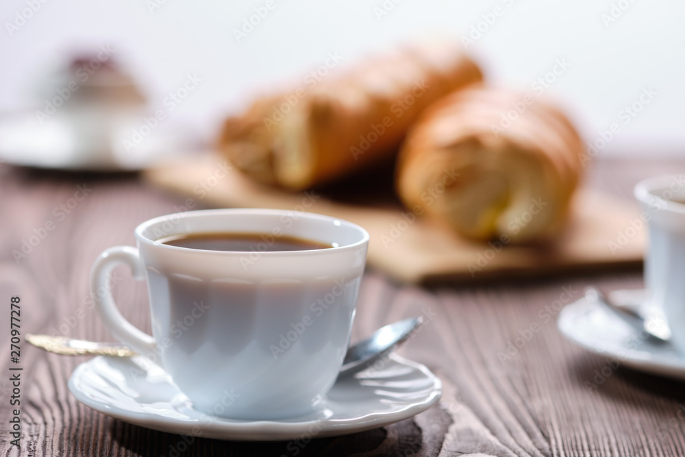 Rolled buns and coffee on wooden table in morning sunlight. Photo with shallow depth of field. Rolled buns and coffee on wooden table in morning sunlight. Photo with shallow depth of field.