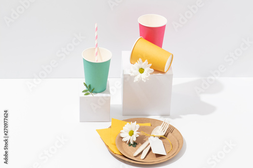 Recyclable multicolored paper tableware, cornstarch cutlery over white © zzzdim