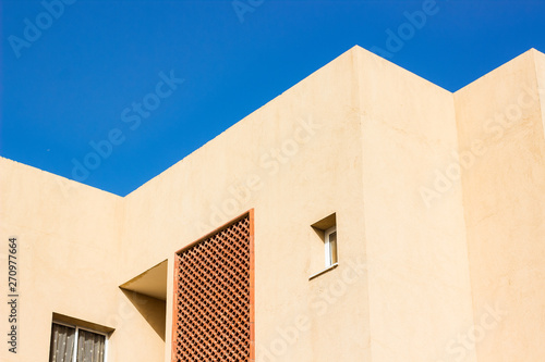 south cottage building geometrical shapes of lines and corners and windows on bright concrete wall, empty vivid blue sky 