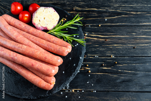 Photography Juicy sausages for barbecue lie on a stone chopping board with rosemary and spic