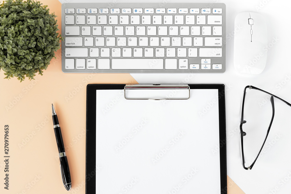 Directly above shot of office desk with potted plant, computer keyboard and mouse, clipboard, eyeglasses and pen on multicolored background. Directly above shot of office desk with potted plant, computer keyboard and mouse, clipboard, eyeglasses and pen on multicolored background.