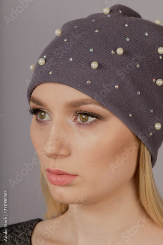 Beautiful girl with natural make-up in a headdress on a gray background.