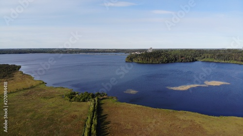 Aerial view of blue lakes and green forests on a sunny summer day in Kavgolovo, Toksovo. Shore of water reservoir with forest under blue sky.  photo