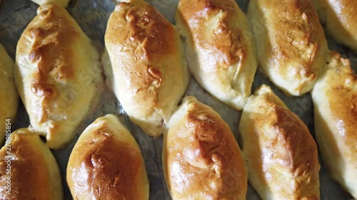 Many traditional delicious baked pasties on tray from oven in bakery. 4K clip with above view