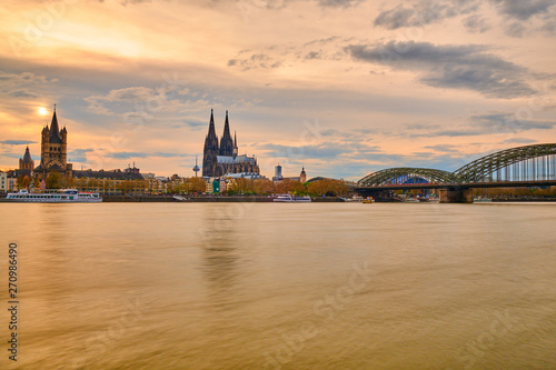 Sonnenuntergang in Köln am Rhein mit Orange Roten Farben am Himmel und Horizont. Blick auf Kölner Dom, Hohenzollernbrücke, Groß St, Martins Kirche und die Kölner Altstadt. Panoarama Hintergrund Poster
