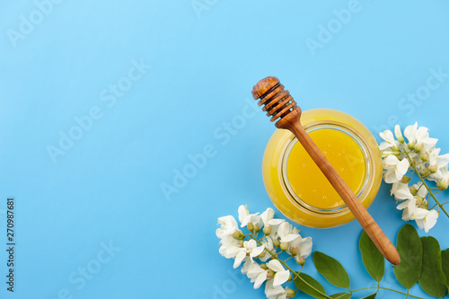 Honey with acacia blossoms on blue background