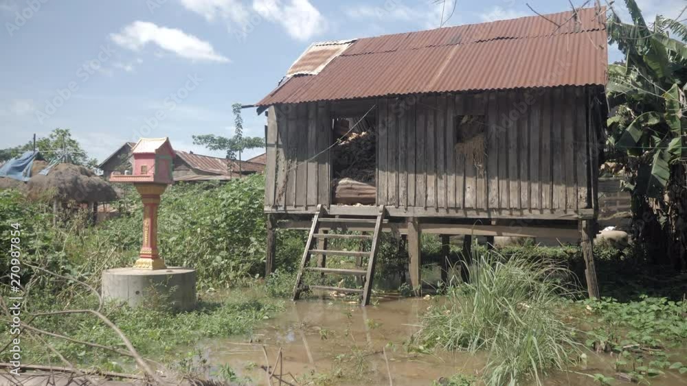 Old stilt house transformed into a warehouse next to a small buddhist temple surrounded by floodwater ( close up) Old stilt house transformed into a warehouse next to a small buddhist temple surrounded by floodwater ( close up)