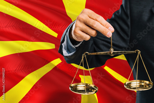 Fotografía Macedonian Judge is holding golden scales of justice with Macedonia waving flag background