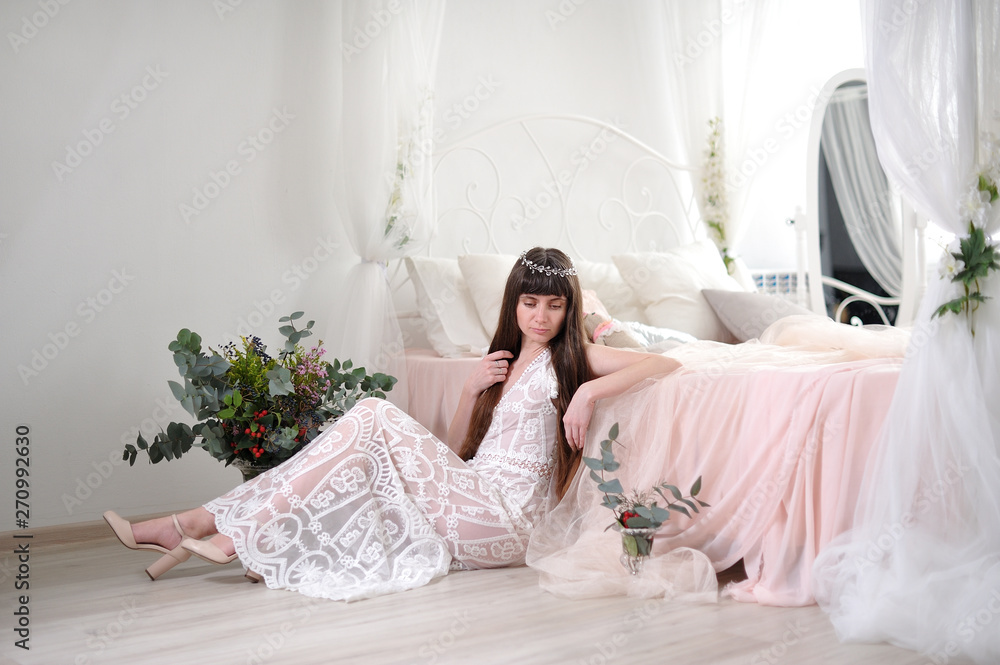 Photo of a young girl in the style of fine art. The girl in a white translucent dress sits on the floor next to the bed and looks into the camera. Girl in dress sits on laminate floor Photo of a young girl in the style of fine art. The girl in a white translucent dress sits on the floor next to the bed and looks into the camera. Girl in dress sits on laminate floor
