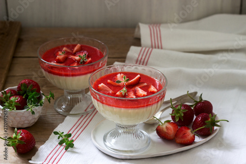 Panna cotta with strawberry sauce and strawberry slices, decorated with thyme leaves. Rustic style.